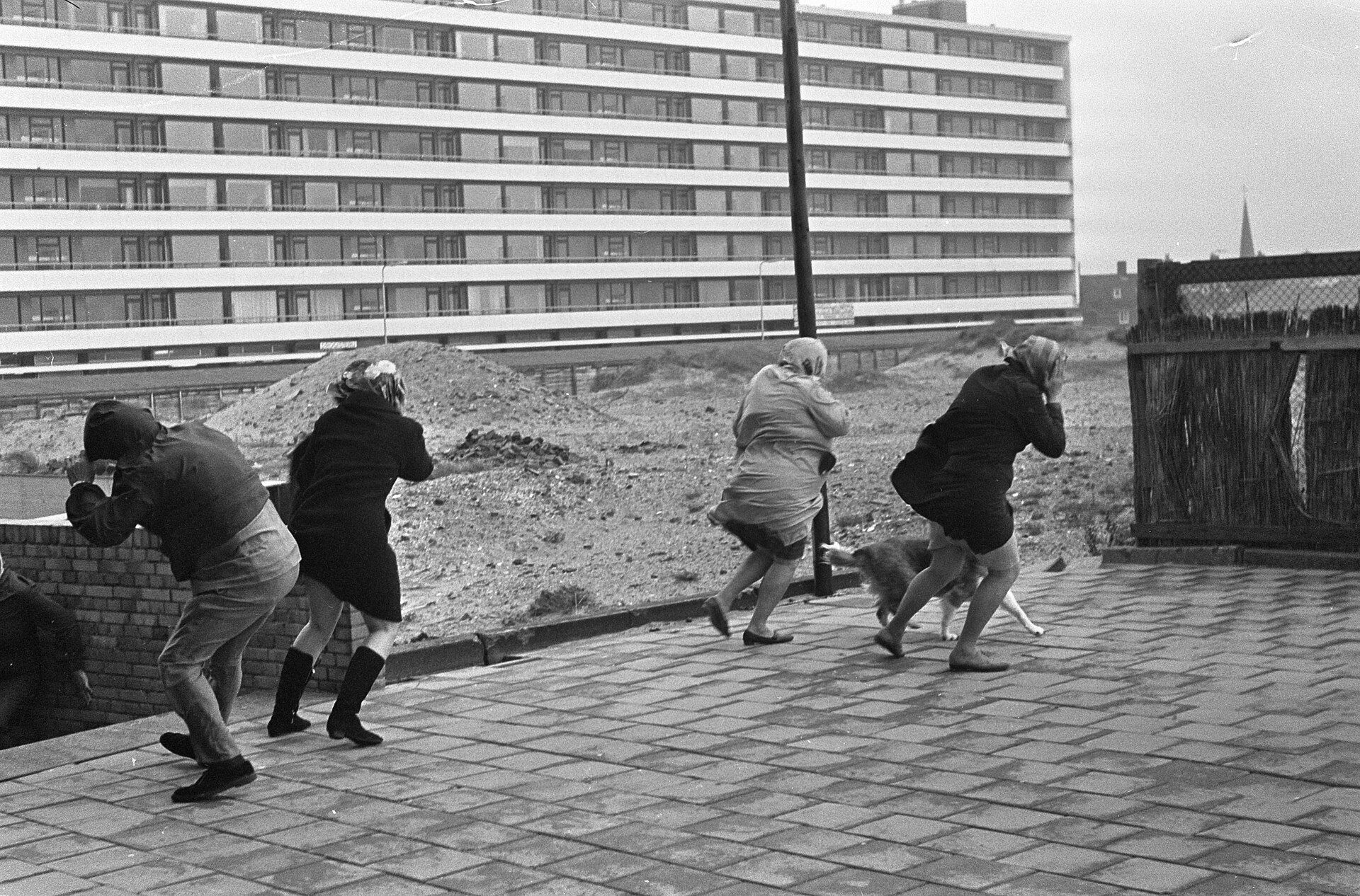 Zwart-witfoto uit 1967: vier mensen lopen voorovergebogen tegen de storm in op de boulevard van Zandvoort