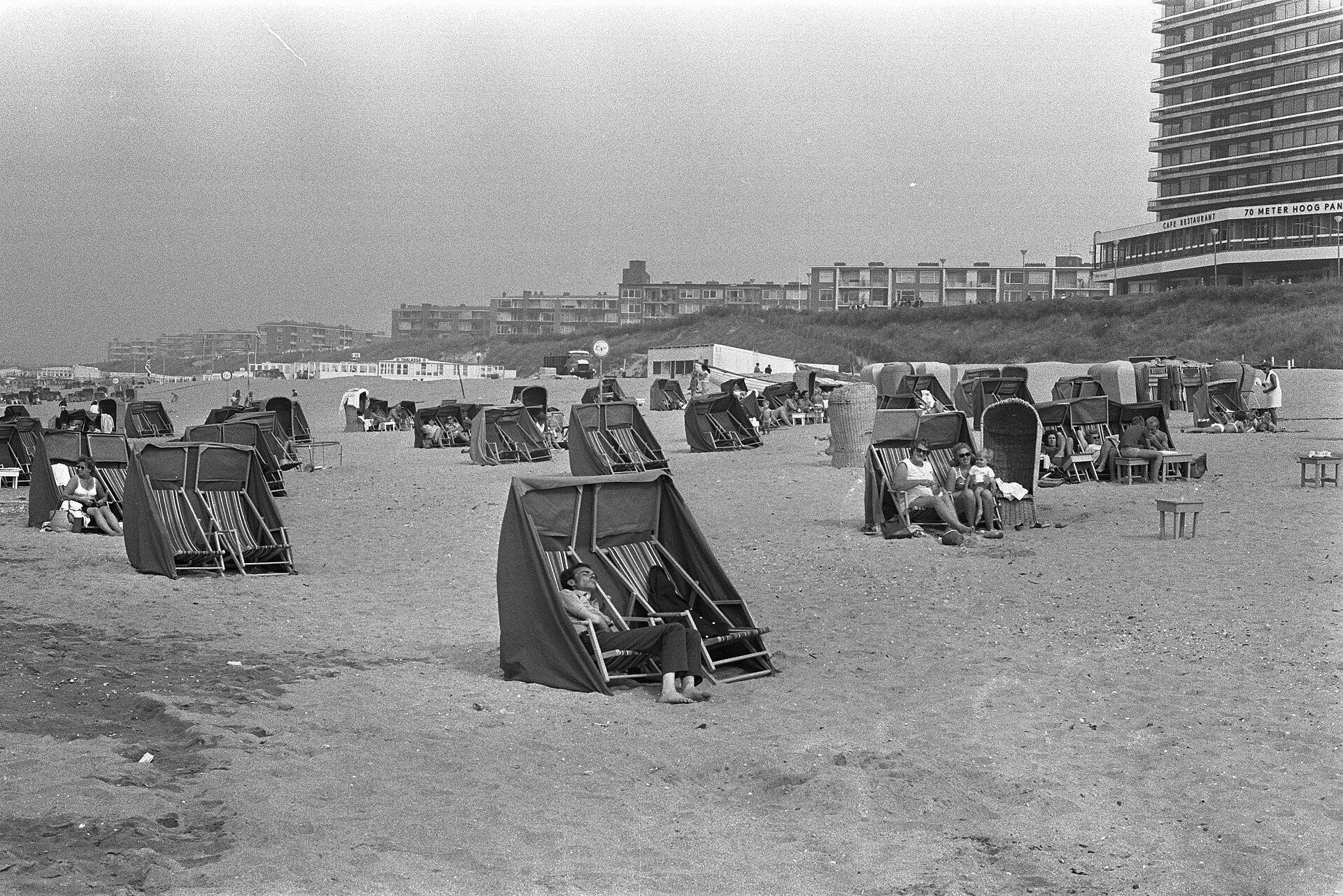 Zwart-witfoto uit 1971: mensen in rieten strandstoelen op het strand van Zandvoort in de najaarszon