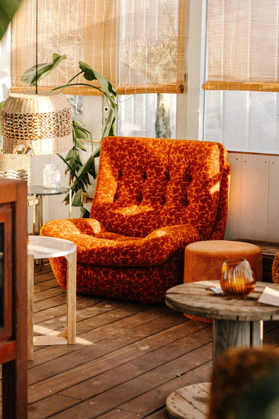 De lounge van NIUS: een oranje fluwelen fauteuil, planten en kaarslicht bij het raam